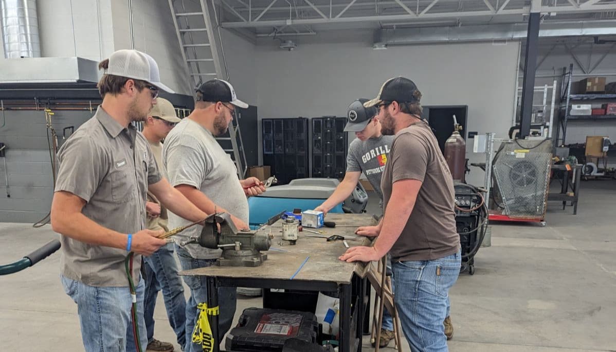 Group of five people at a work table using tools