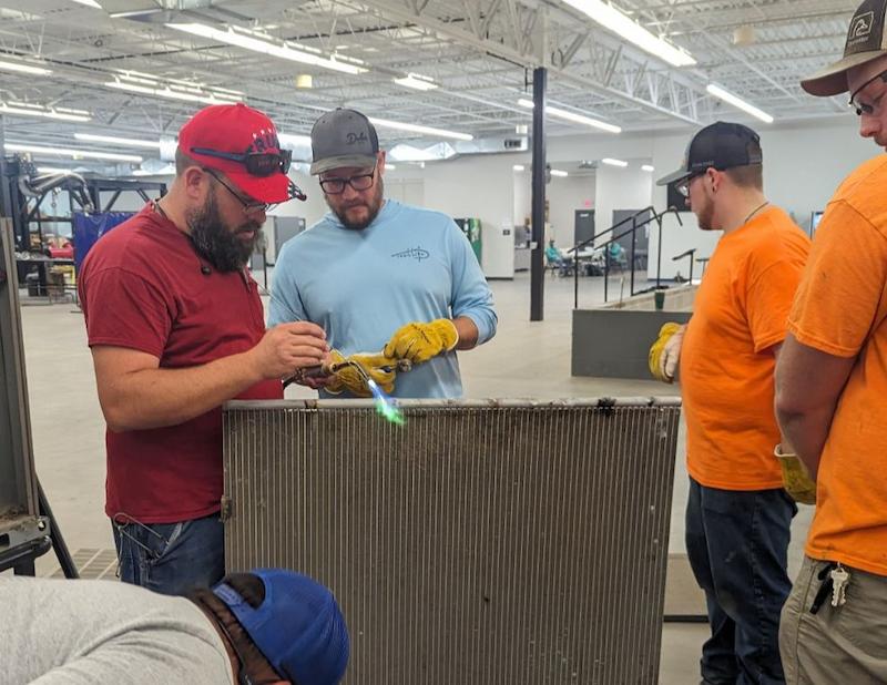 Men welding something with two others watching
