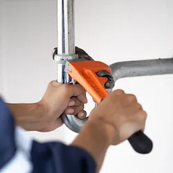 Person doing plumbing work with an orange wrench