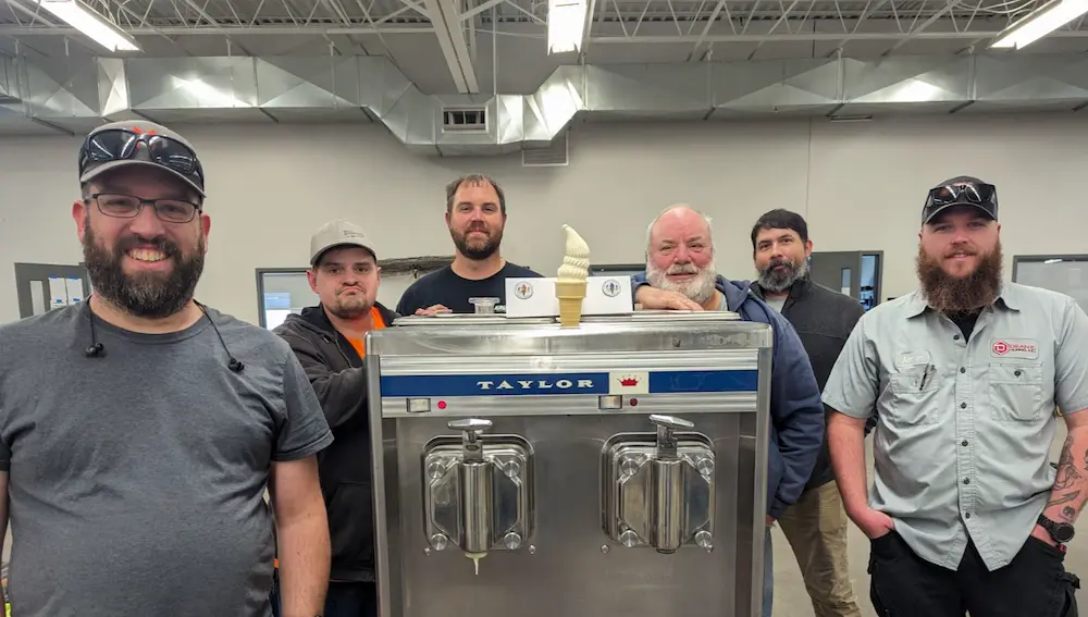 Six people standing around a Taylor brand ice cream machine