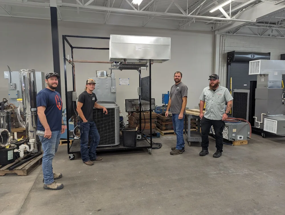 Four men standing around equipment and looking at the camera smiling